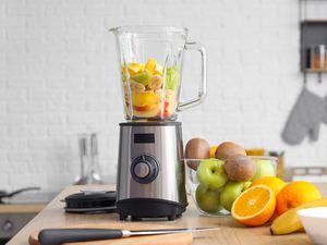 A blender with fresh fruit on a kitchen table
