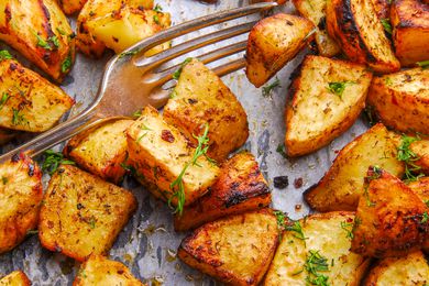 Close up of roasted potatoes in a baking pan, topped with fresh dill