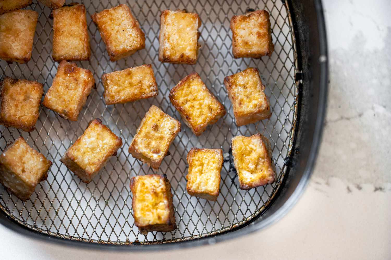 Crispy cubes of tofu in an air fryer basket