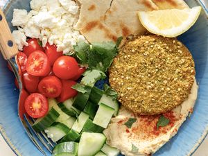 overhead view of Falafel Bowl - pita, feta, falafel, hummus, lemon slice, cucumbers, and grape tomatoes