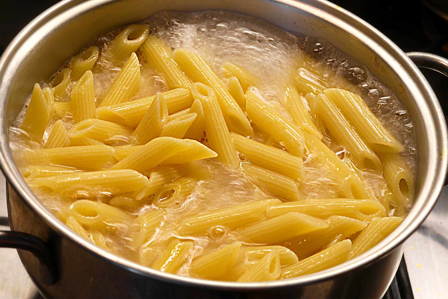 A pot of penne pasta boiling in water