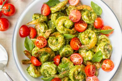 5-Ingredient Pesto Shrimp with Cherry Tomatoes in a Bowl Next to Cherry Tomatoes on a Vine