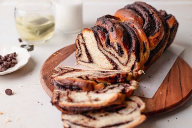 Semi-sweet chocolate babka on a wooden serving platter and three slices cut and laid in front.