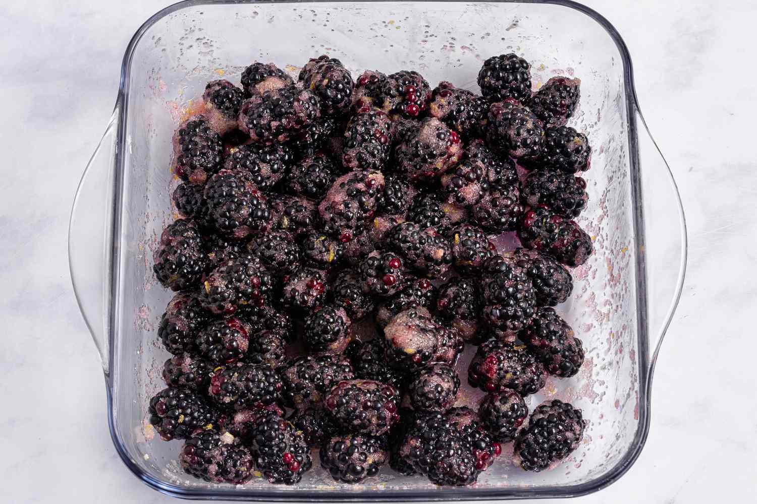 Overhead view of of a baking dish with blackberries in the bottom to make a blackberry cobbler recipe.