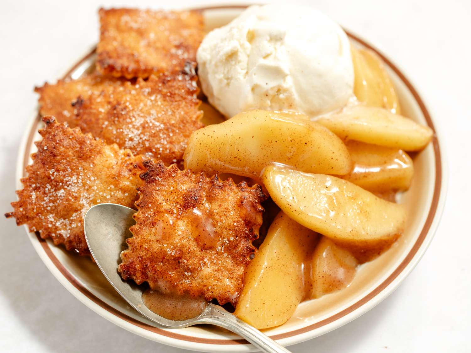 short-cut apple pie in a bowl with a spoon (close-up)