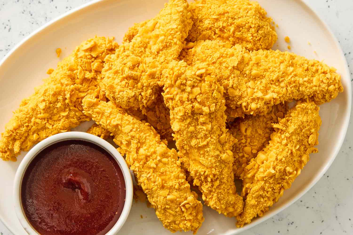 Plate of crispy chicken tenders with a small bowl of dipping sauce