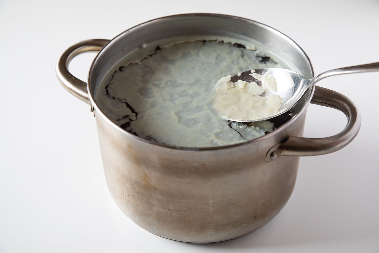 Removing the hardened fat from a pot for a beef bone broth recipe.