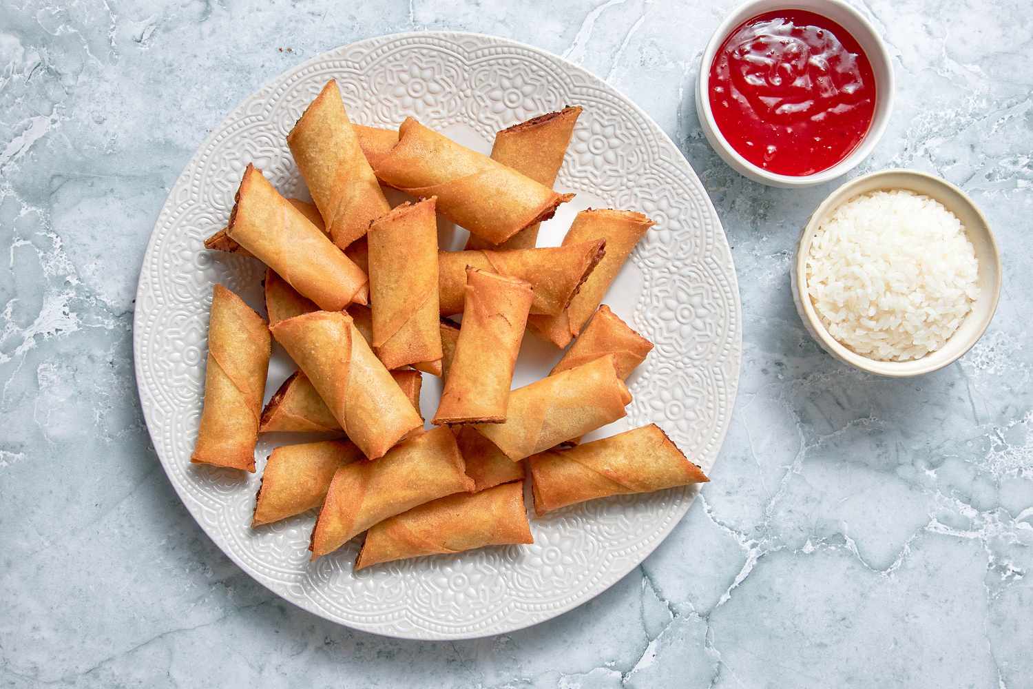 Plate of Lumpia Next to a Bowl of Rice and a Bowl of Sweet and Sour Sauce