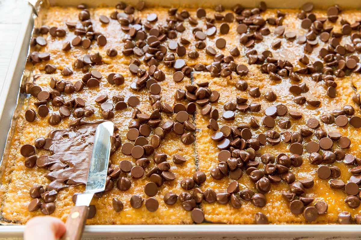 Chocolate Matzo Toffee Recipe - warm chocoalte chips being spread over toffee