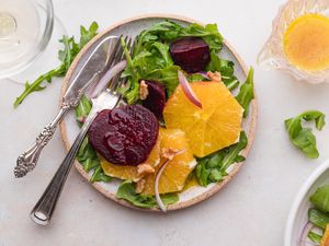 Pouring vinaigrette over a salad of beets and oranges.