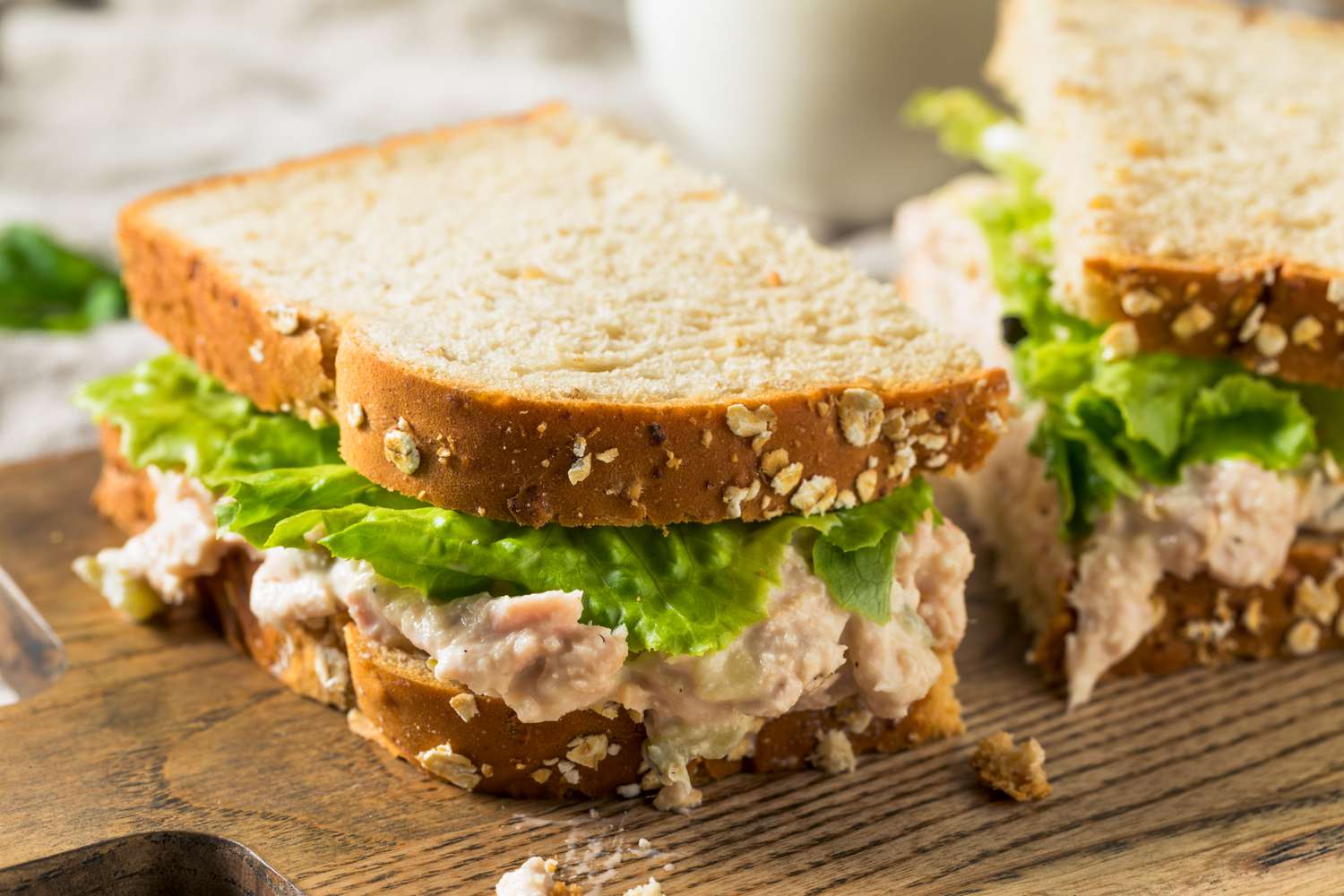 Tuna salad sandwiches with lettuce on wheat bread on a wooden surface
