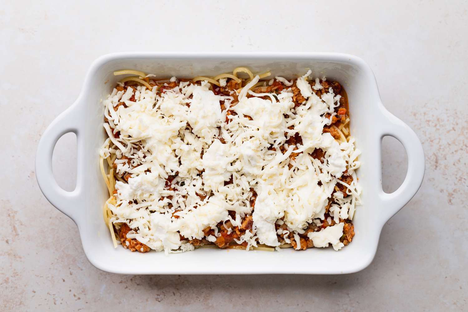 Baked Spaghetti topped with cheese and ready to bake
