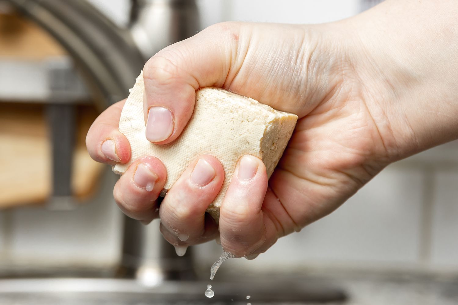 Hand Squeezing Liquid from Block of Tofu for Sofritas Recipe