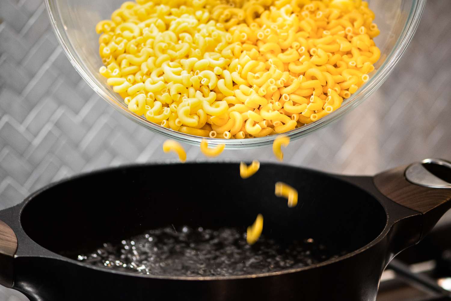 Bowl of Elbow Macaroni Poured into a Pot of Boiling Water for Cheeseburger Casserole Recipe