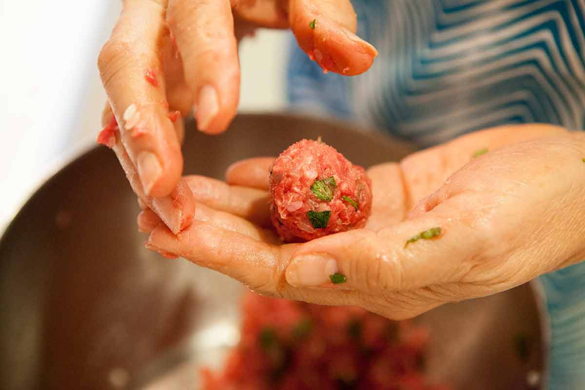 A meatball being formed in a pair of hands