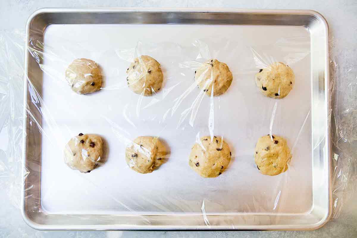 Shaped hot cross buns rising on a baking sheet
