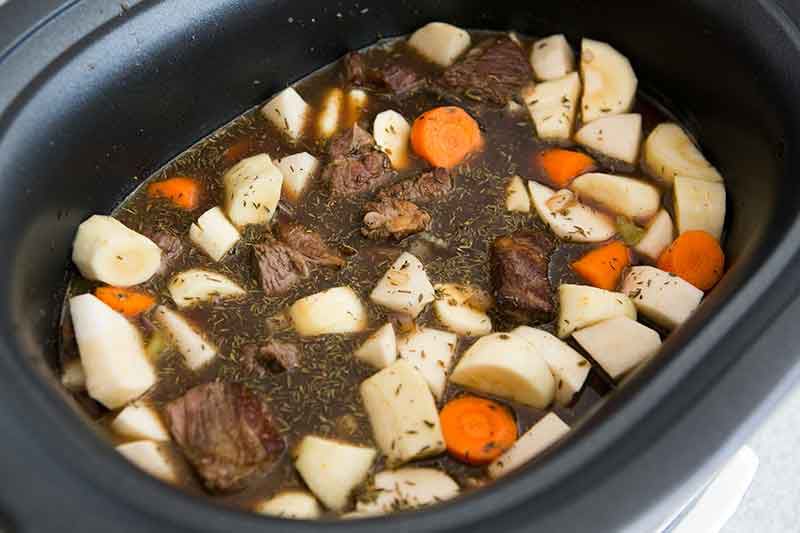 Crock pot Guinness beef stew being prepared and made ready to cook in slow cooker 