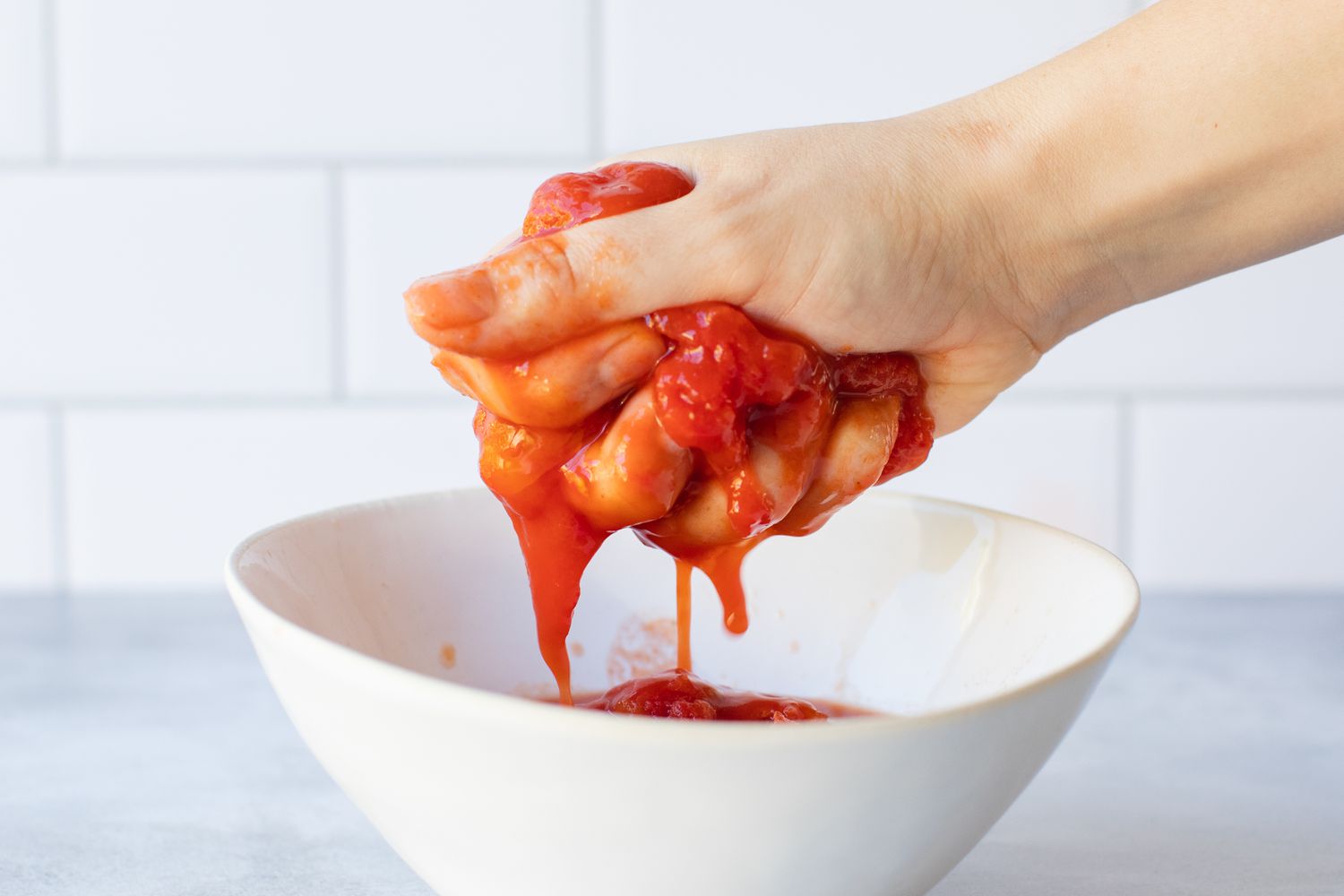 Crushing tomatoes by hand for homemade marinara sauce