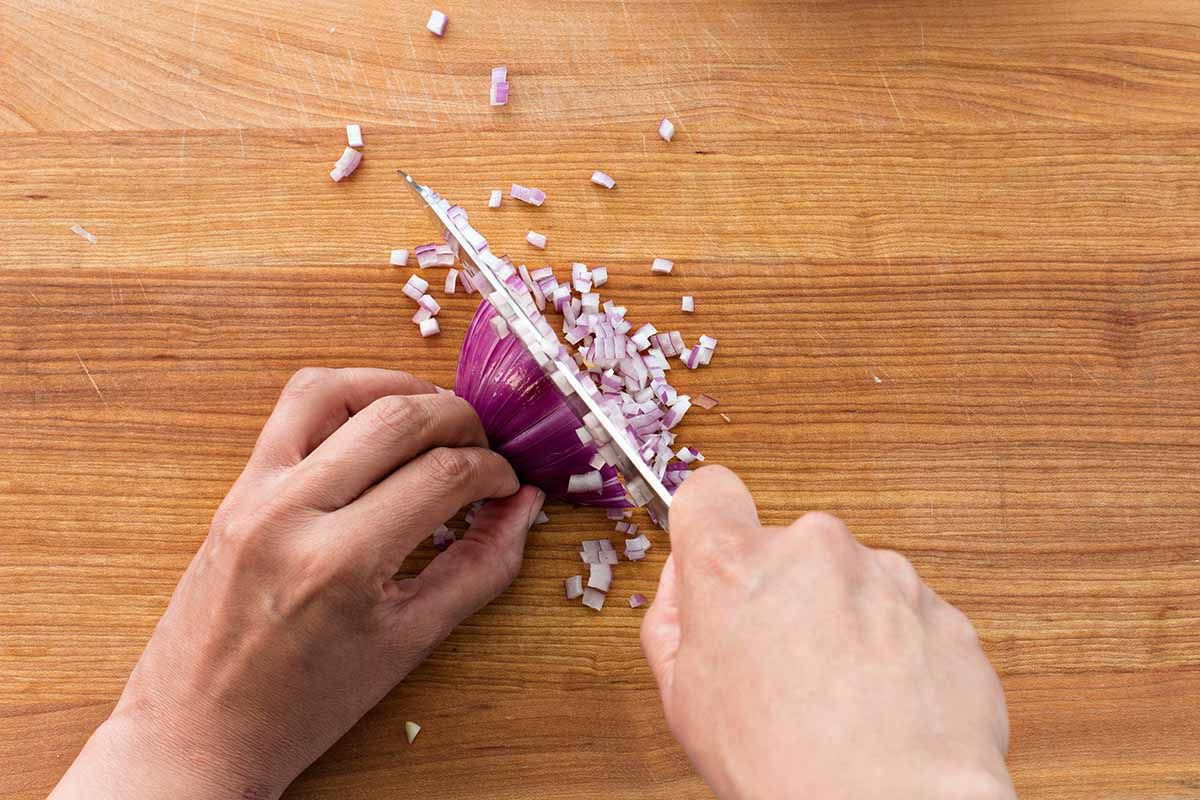 Copycat Guacamole Recipe - person mincing an onion