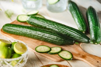 Four large green cucumbers top view composition on a wood chopping table and some slices