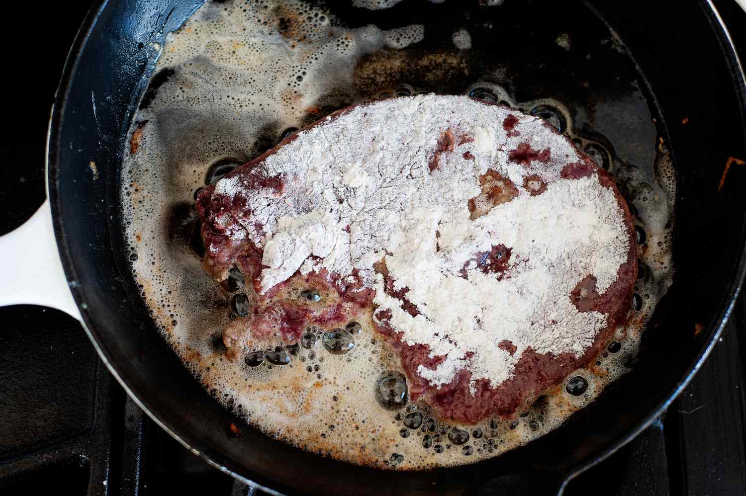 A skillet with liver coated in flour to show how to cook liver.