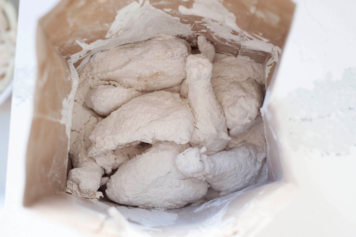 Shaking chicken in a flour mixture to make chicken fried chicken.