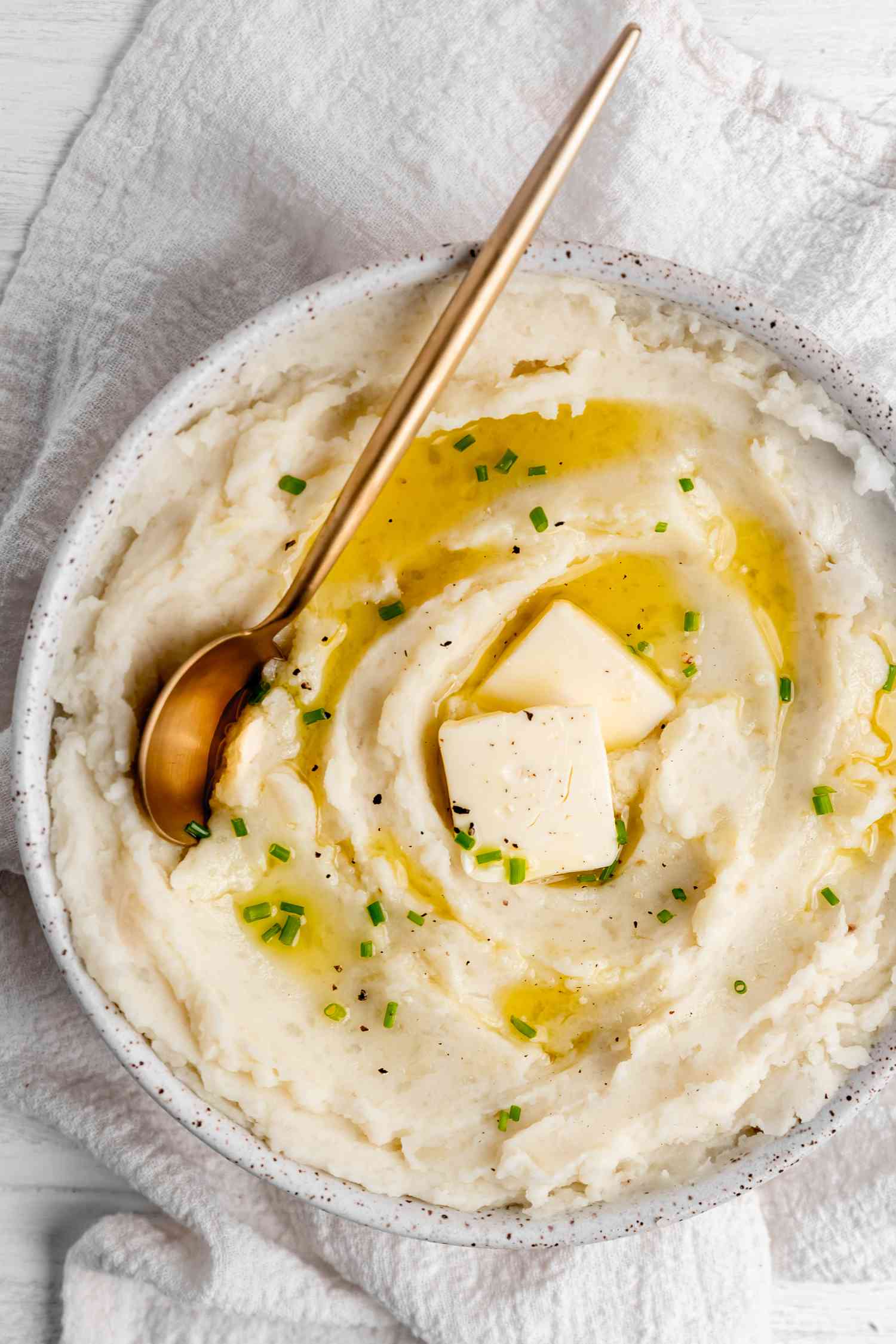 Vegan Mashed Potatoes in a Bowl Topped with Butter, Cracked Pepper, and Chives