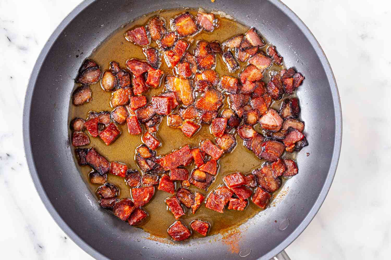 Cooked chorizo and bacon in a skillet to make Spanish Style Migas.