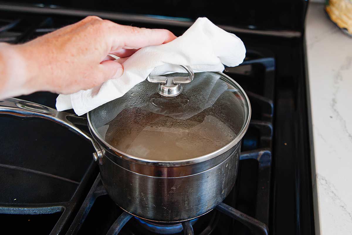 Cooking Brown Rice on the Stove Top with a hand on a lid