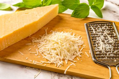 A block of cheese grated on a cutting board