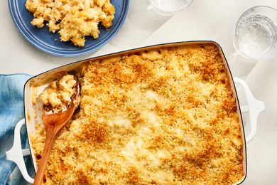 Overhead view of a baking dish of macaroni and cheese topped with panko, a serving spoon in the corner next to a small blue plate with a serving