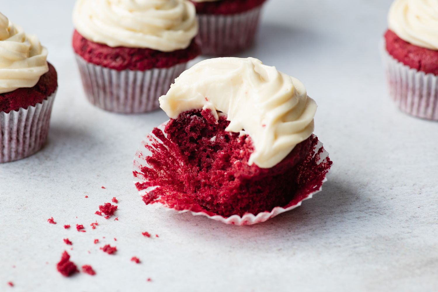 A red velvet cupcake set in a cupcake liner with a bite taken out of it.