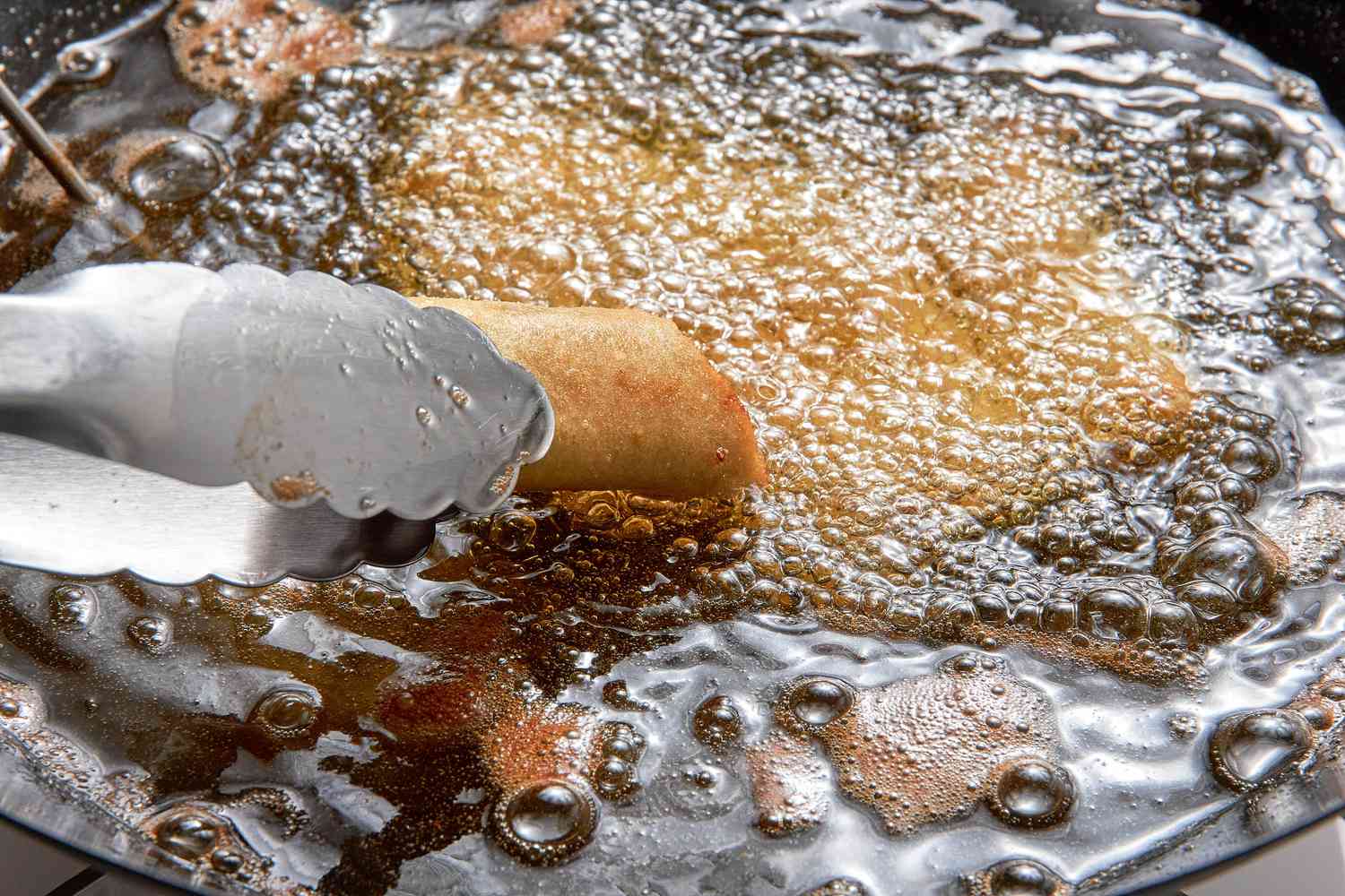 Tongs Removing Cooked Lumpia From the Hot Oil for Filipino Lumpia Recipe