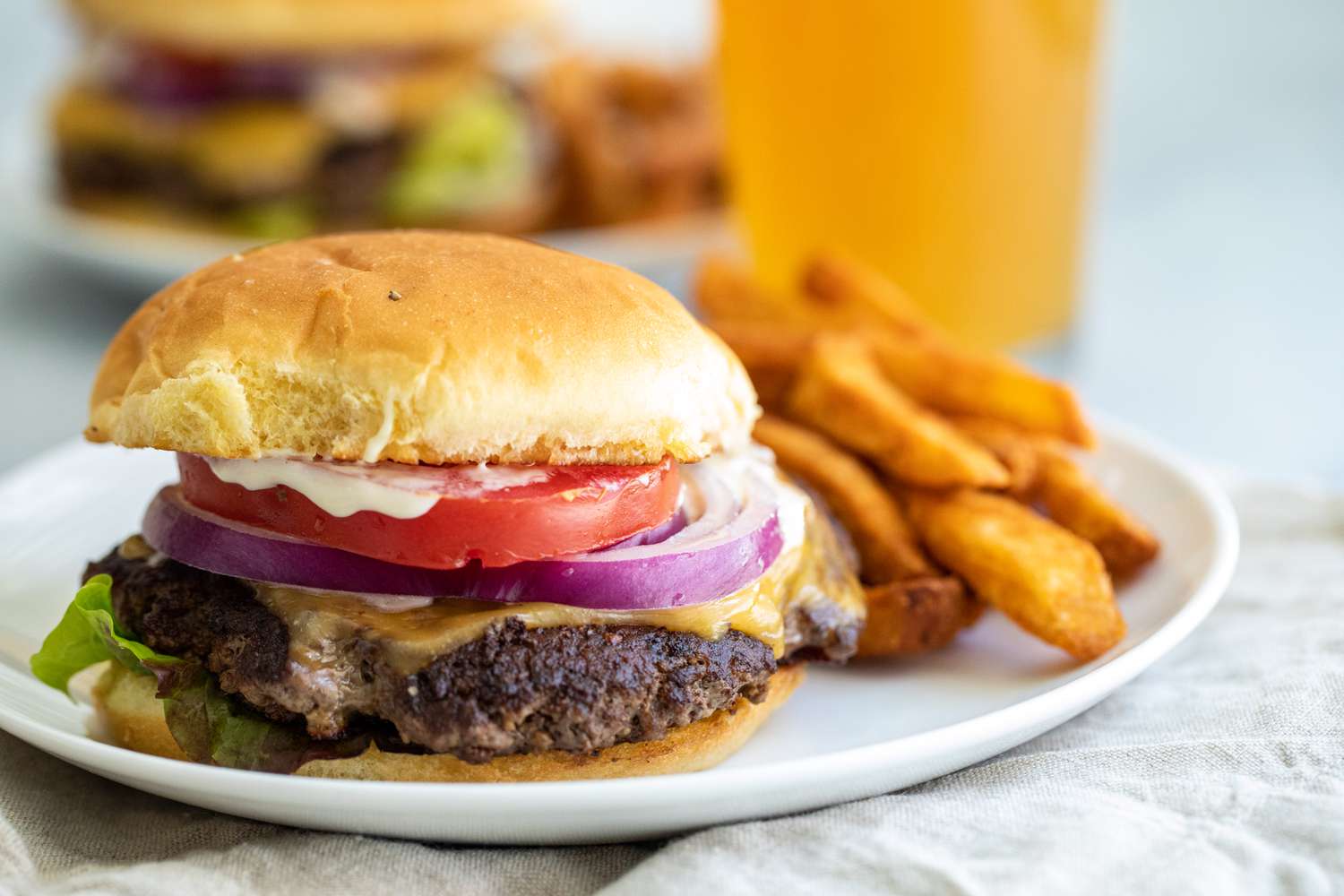 Side view of a homemade smashburger on a plate with fries.