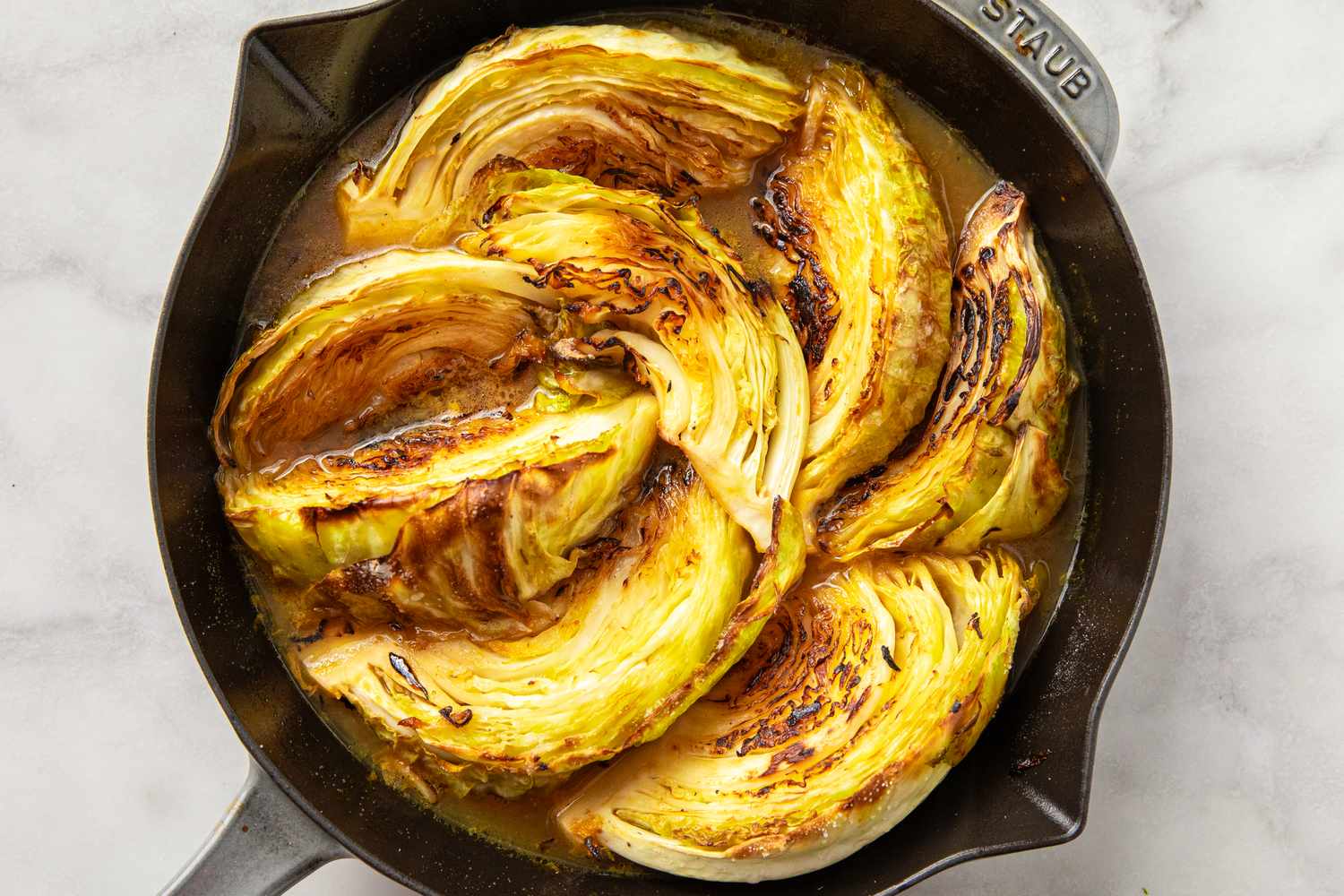 Cooked wedges of cabbage arranged in a skillet