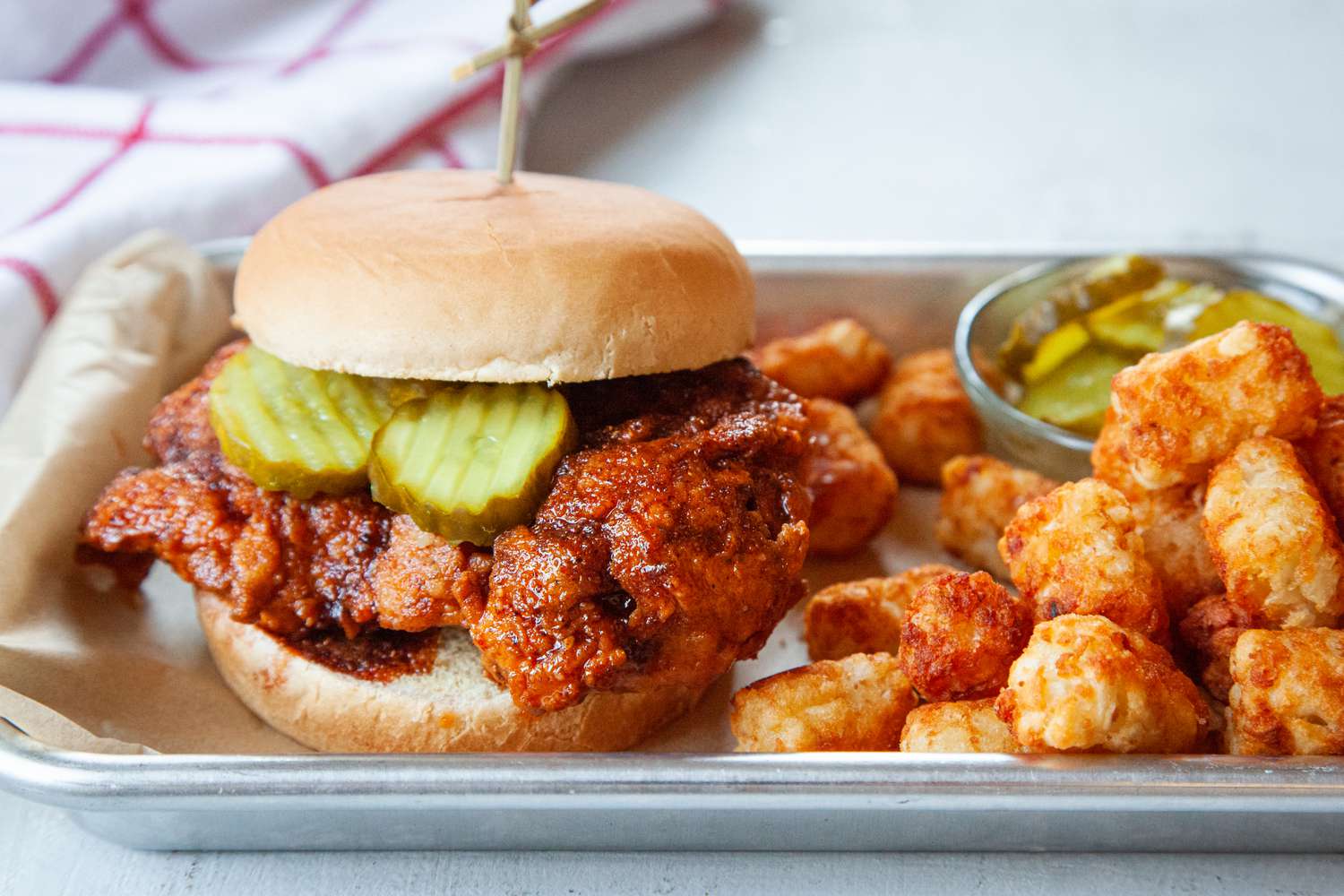 Nashville-style hot chicken served on a parchment lined tray along with tater tots.