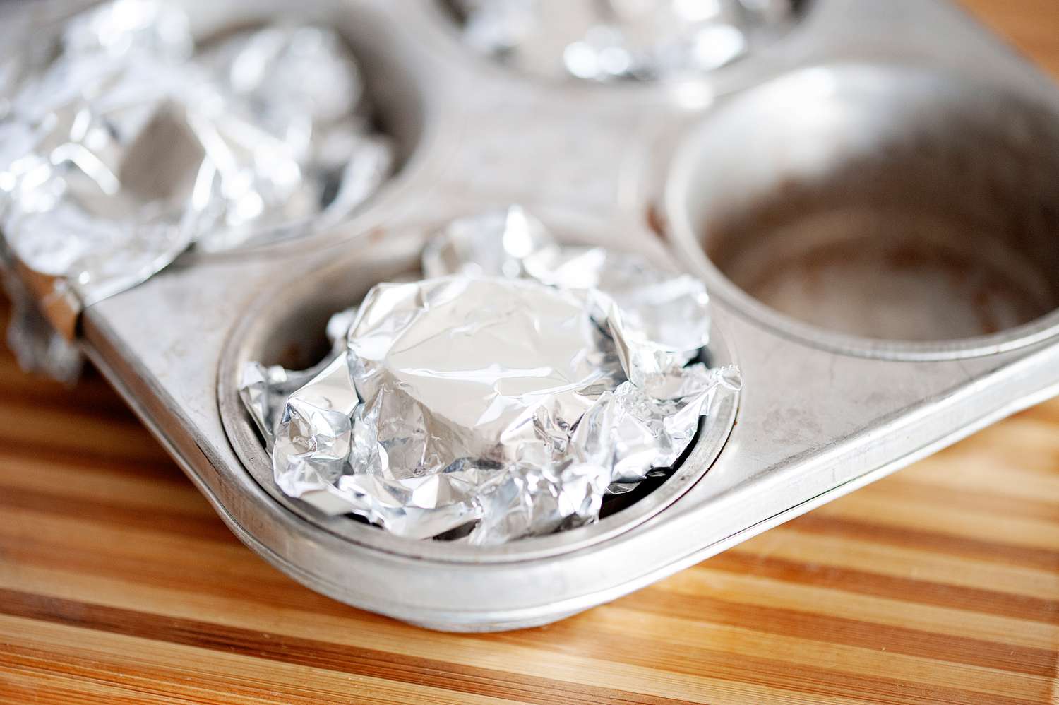 Foil wrapped head of garlic in a muffin tin.