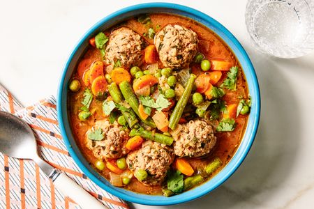 A bowl of albondigas soup with meatballs and vegetables