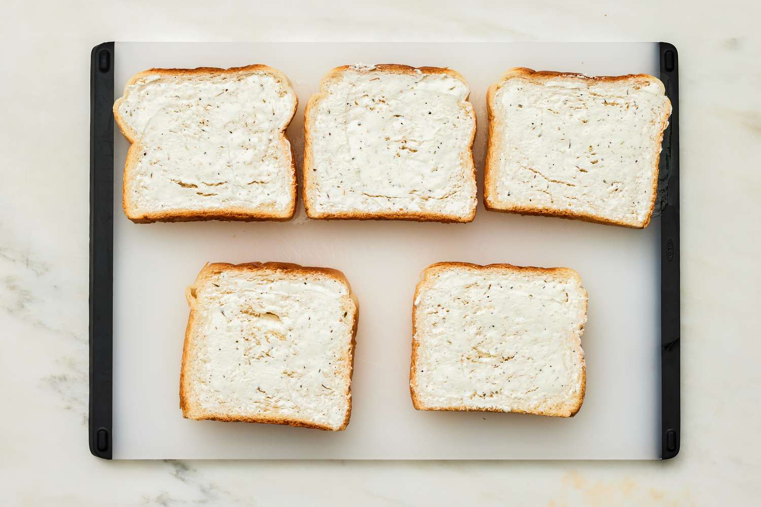 Five Bread Slices Covered With Goat Cheese on a Cutting Board