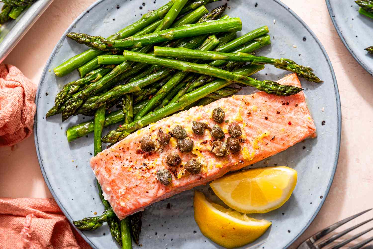 sheet pan salmon and asparagus on a plate with lemon slices