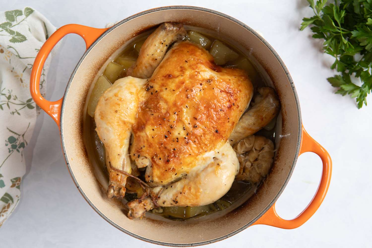 A roasted chicken in a pot with garlic and vegetables