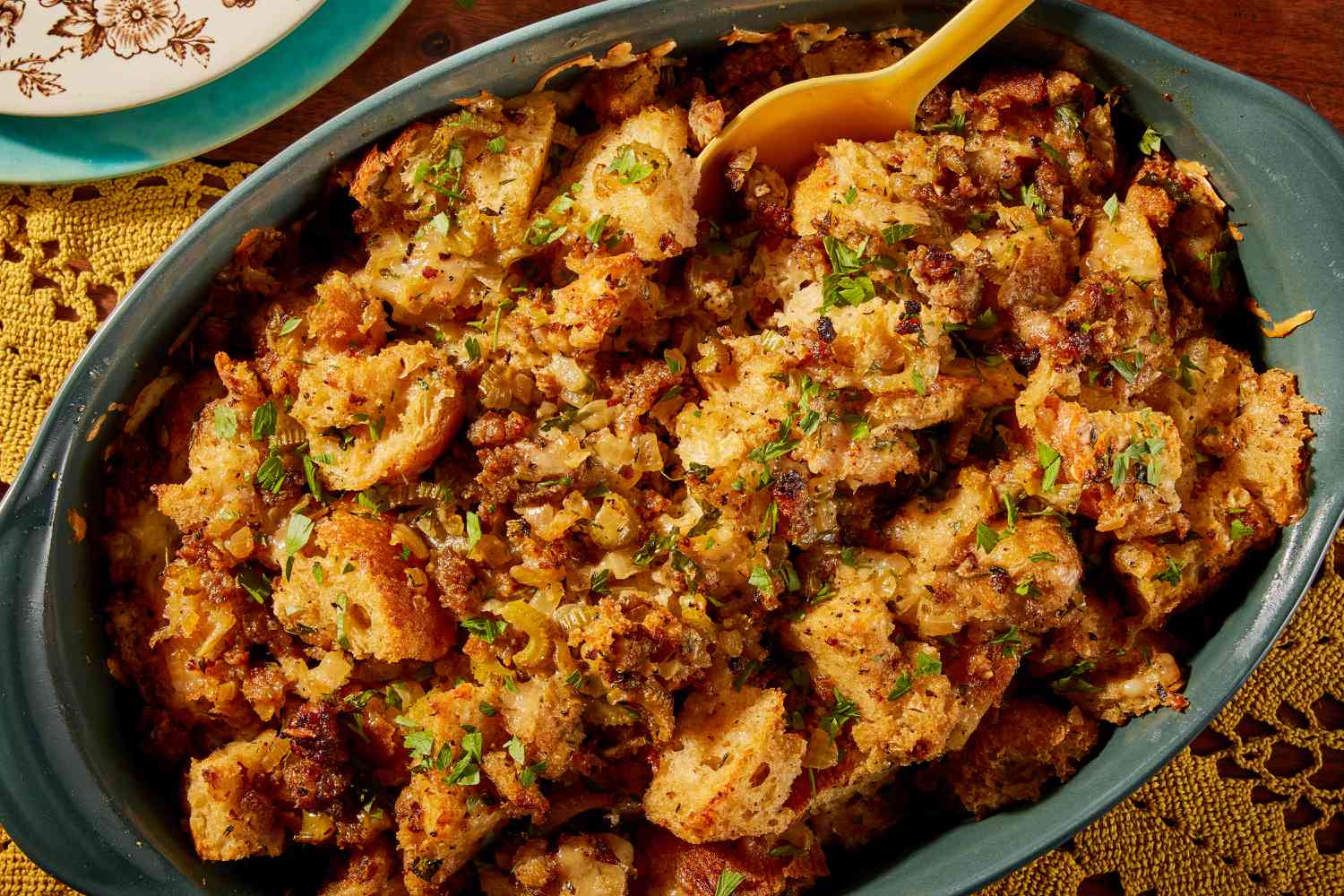 Overhead view of a green casserole dish of Wisconsin-style stuffing over a yellow doily on a wooden tabletop