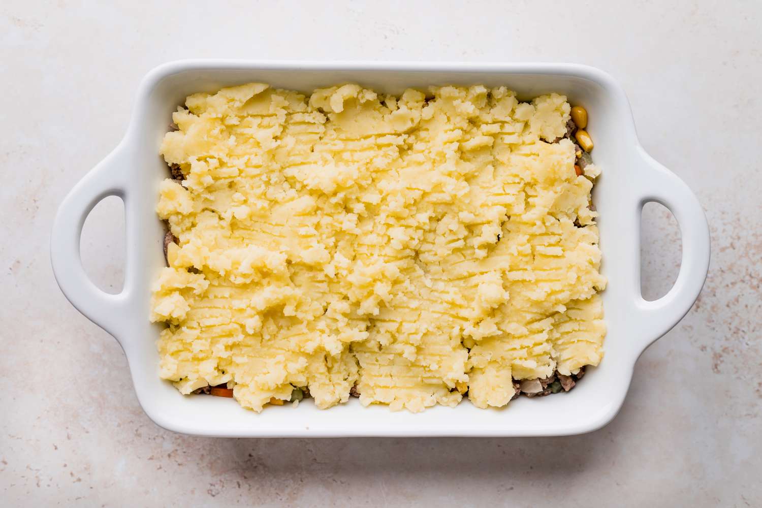 A casserole dish with shepherds pie in it and ready to be baked.