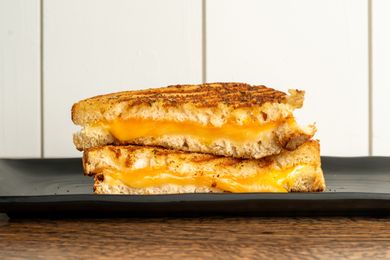 Two halves of a grilled cheese sandwich stacked on a plate