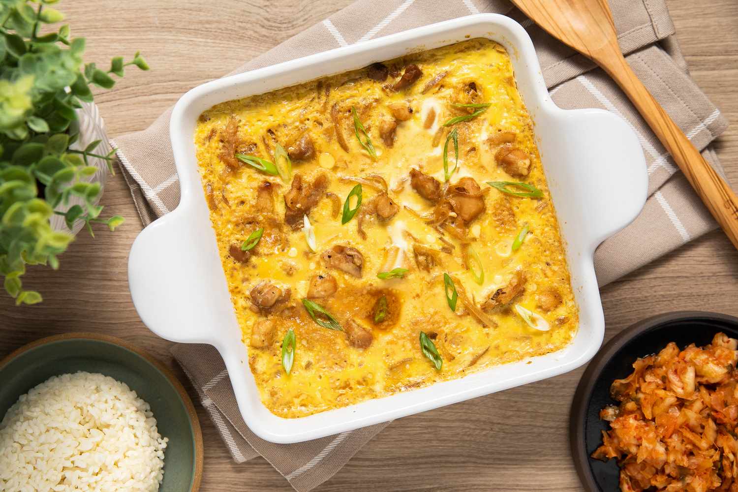 Microwave Oyakodon (Japanese Chicken and Egg Rice Bowl) in a Microwavable Dish Surrounded by a Small Plate With Cooked Rice and a Small Plate of Kimchi