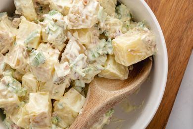 Potato salad in a bowl with a wooden spoon.