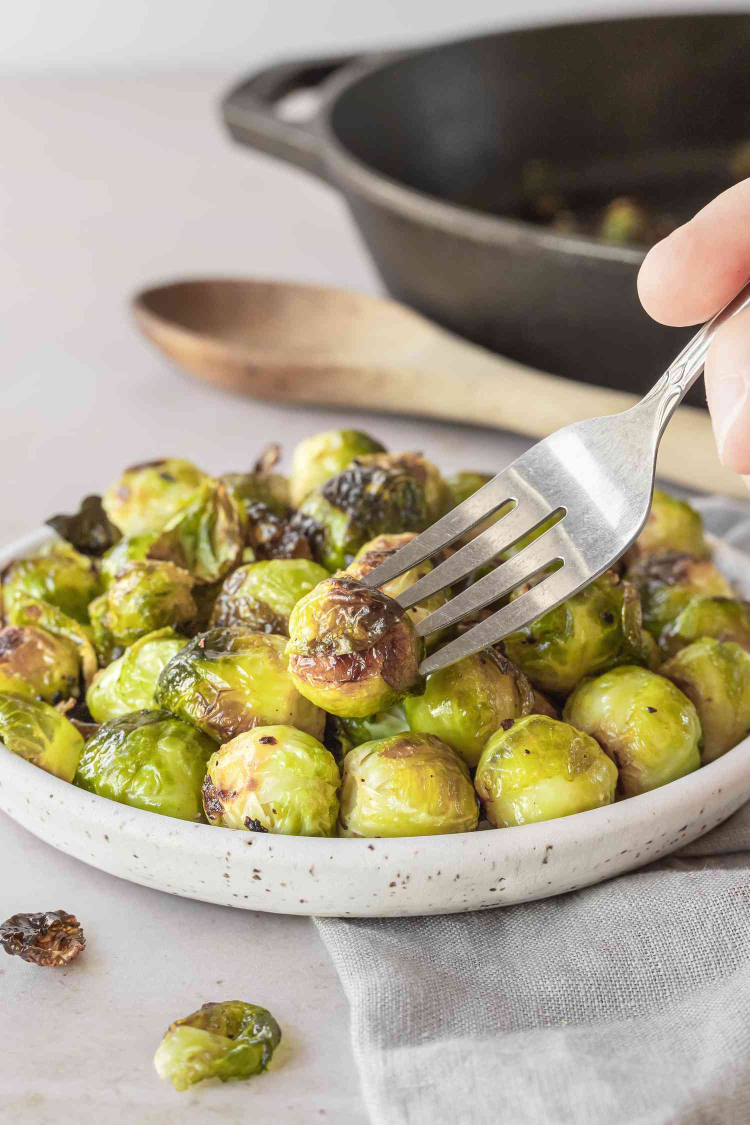 A fork picking up a roasted brussel sprout.