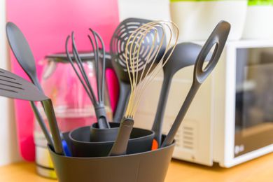 Black plastic cooking utensils in a crock on a kitchen counter