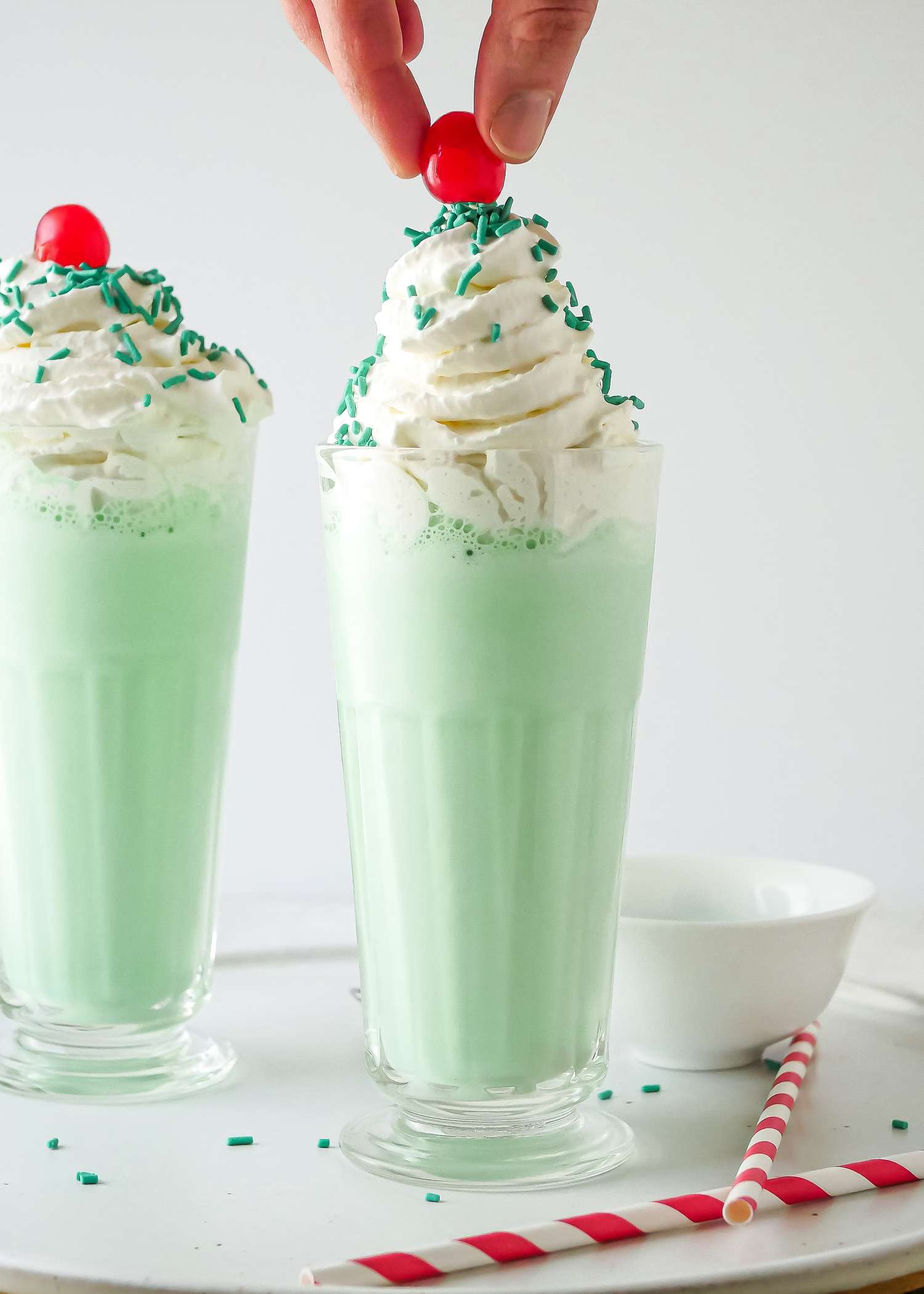 Placing a cherry on top of a Copycat McDonald’s Shamrock Shake.