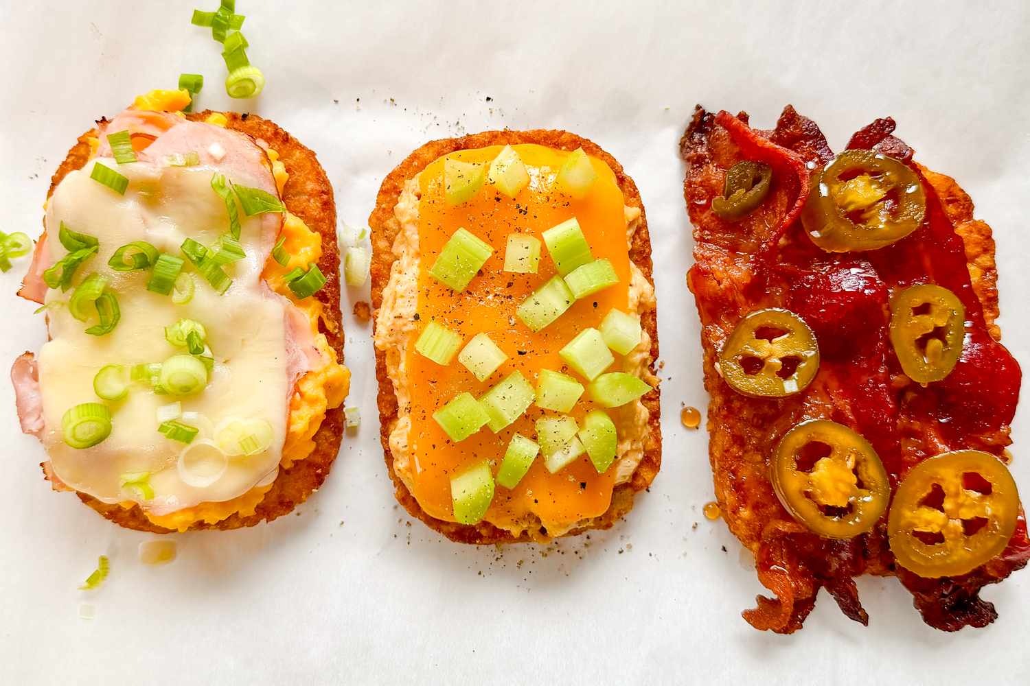 Three pieces of toast topped with cheese vegetables and bacon arranged on a surface
